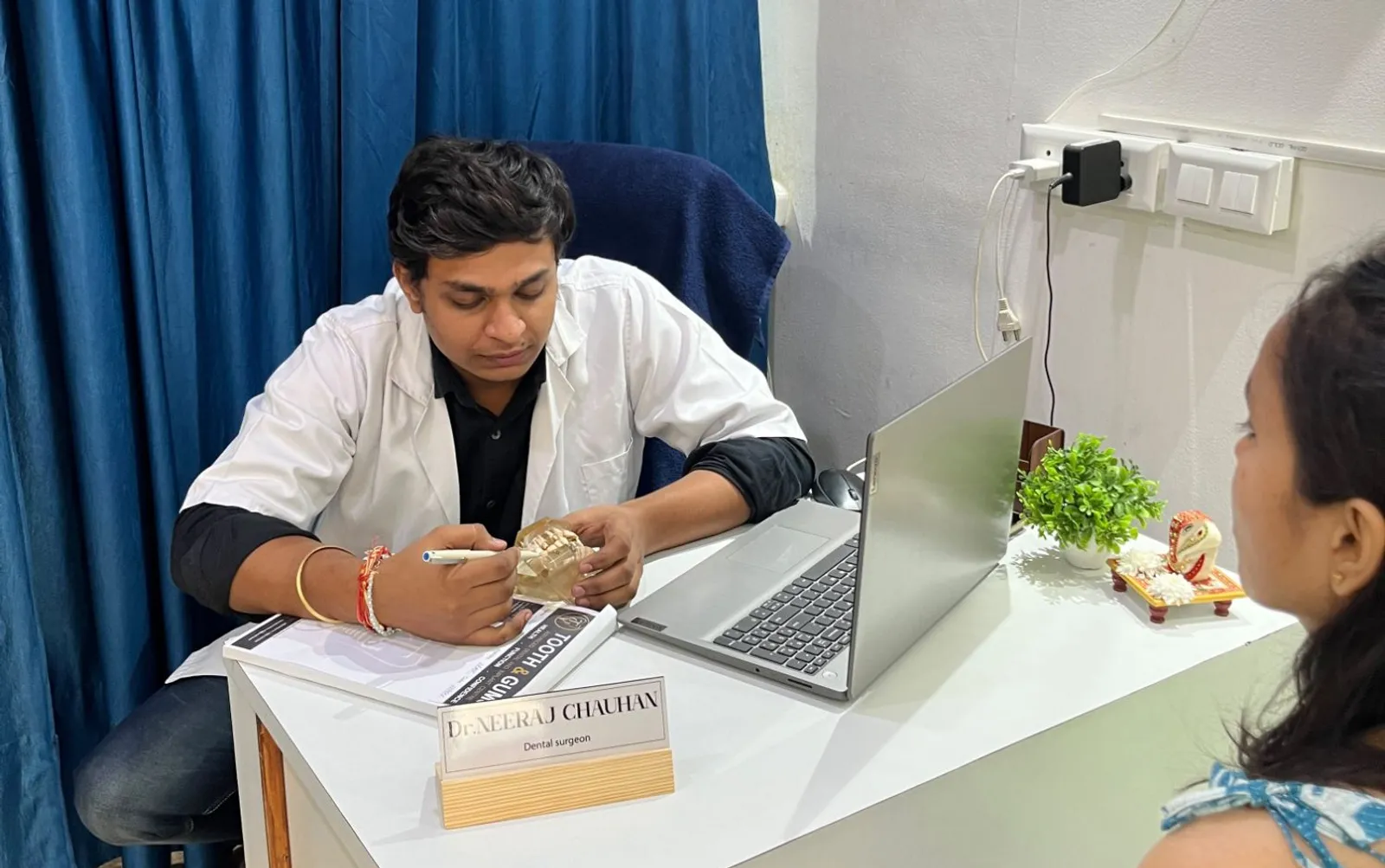 Dr. Neeraj Chauhan explaining treatment to a patient with a dental model at Tooth and Gums